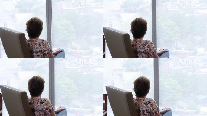 女人坐着看着高层公寓的窗户