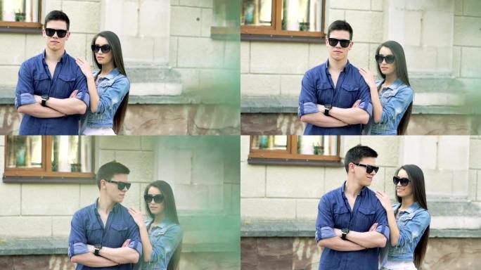 一对戴着墨镜的夫妇站在街上看着一边。慢慢地
