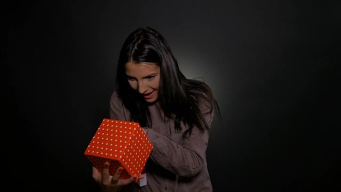 年轻女子打开礼品盒，对礼物感到惊讶