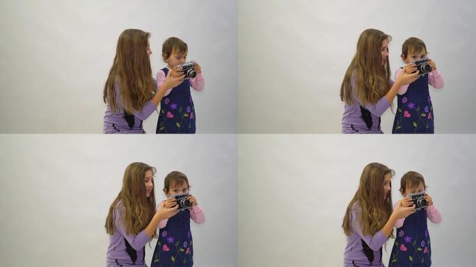 小女孩和她的姐姐用白色背景的老式相机