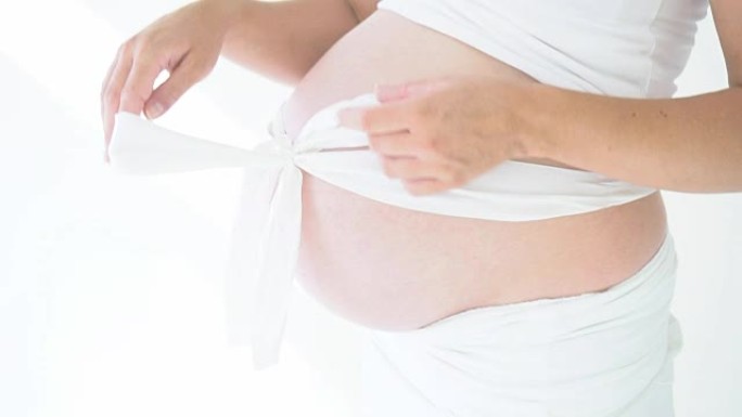 孕妇的肚子用白色蝴蝶结闭合