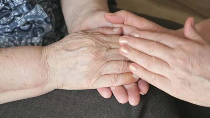 女人抚摸着一个皱着皱纹的老女人的手