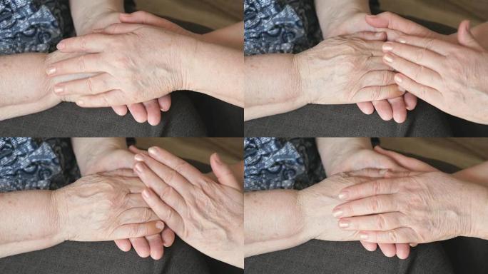 女人抚摸着一个皱着皱纹的老女人的手
