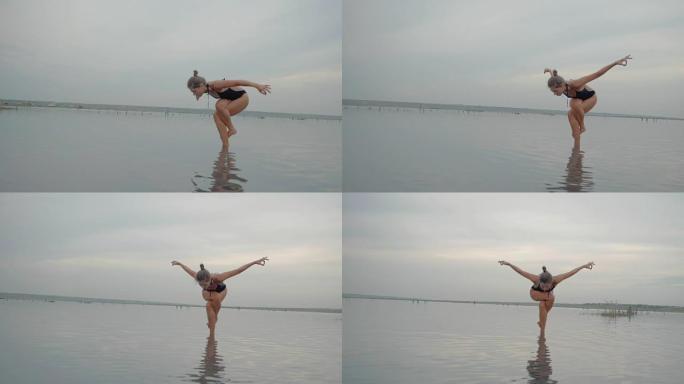 穿着泳衣的年轻白人妇女在水里曼，湖或河里练习瑜伽。美丽的倒影。复杂的体式，平衡。健身、运动、瑜伽和健