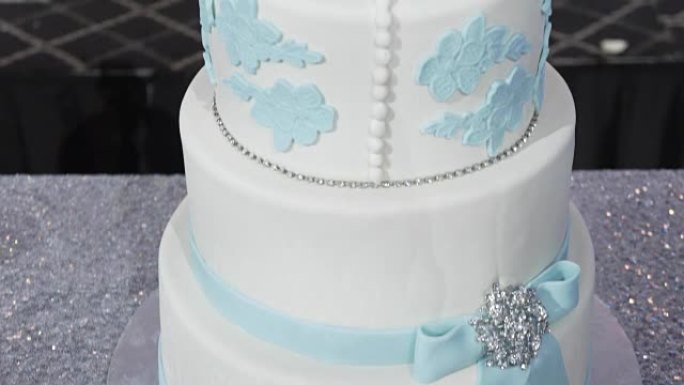 银色底座上有多层白色结婚蛋糕，顶部有粉红色花朵。非常漂亮的结婚蛋糕。庆祝或婚礼用的二分蛋糕。蛋糕
