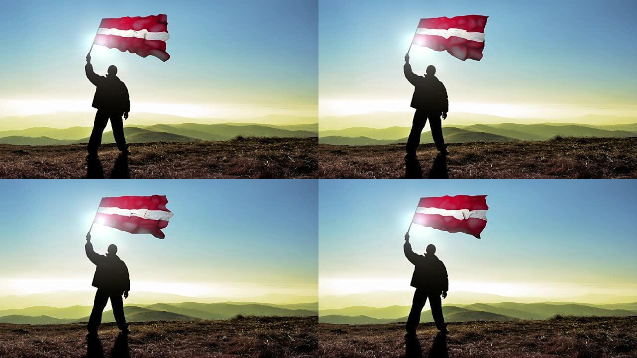 成功的剪影男子冠军挥舞拉脱维亚国旗山顶，Cinemagraph循环背景