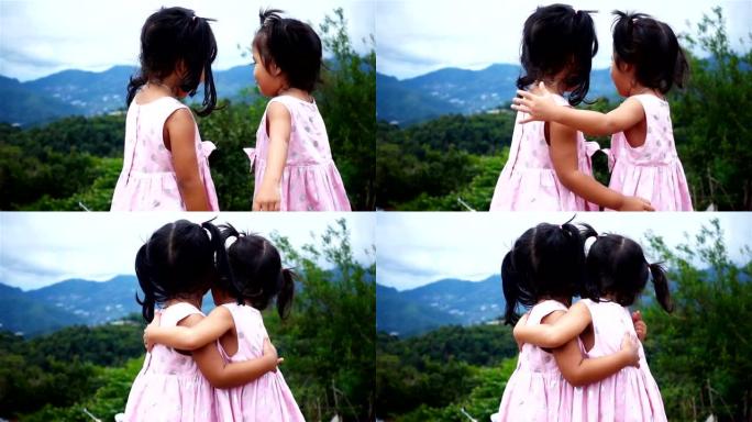 亚洲快乐的拥抱和微笑两个背景山的小女孩，超级慢动作
