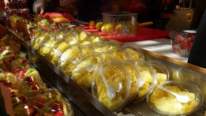 新鲜切片水果站在食品市场，街头食品现场，手持镜头