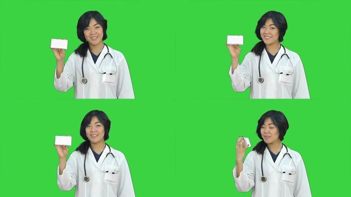 亚洲女医生在绿屏上展示一瓶平板电脑看着相机，色度键