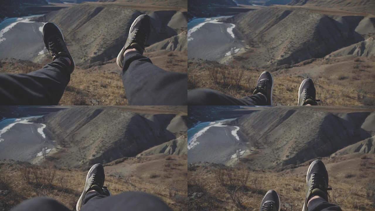 游客坐在悬崖的边缘，用脚颤抖