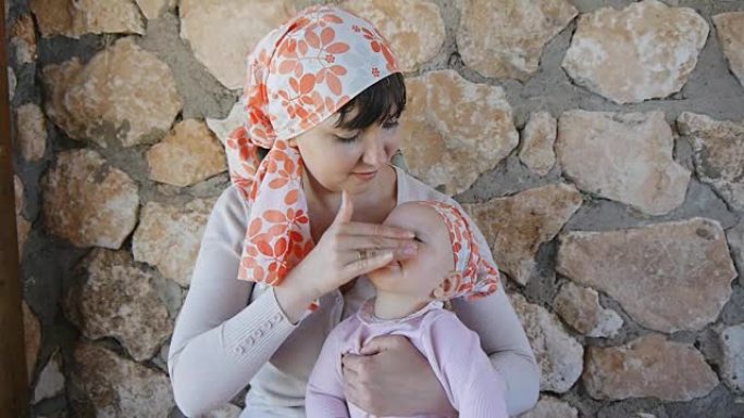 年轻的母亲在婴儿身上涂上防晒霜