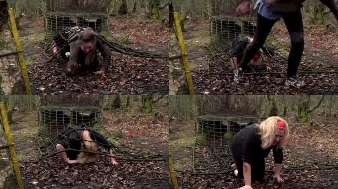 在突击路线/障碍路线上爬过网隧道的妇女-慢动作