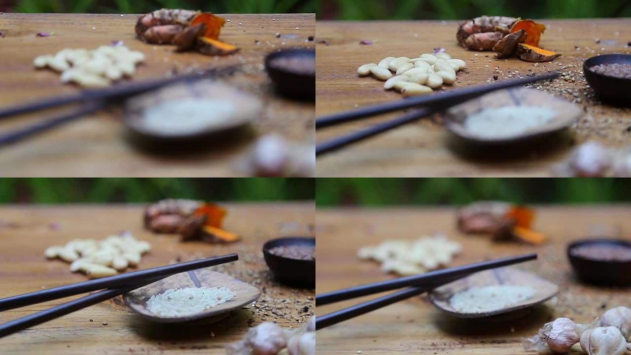 桌子上有空间的姜黄，大蒜，杏仁，亚麻籽的背景上有干米饭的黑筷子
