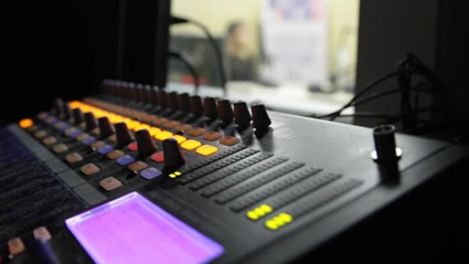 在直播电视转播期间，专业音频操作员在音频混合器旋钮上工作。