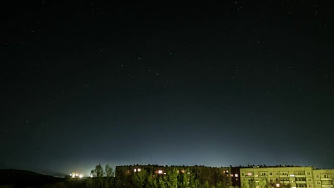 星空在房屋背景下的时间表，窗户上的灯光亮着。哈萨克斯坦塞米巴拉金斯克