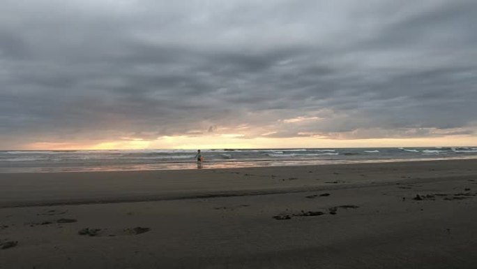 日落时在新西兰Murawai海滩上玩耍的小男孩超级英雄