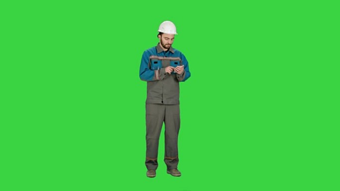 建筑工人使用手机在绿屏上发送消息，色键