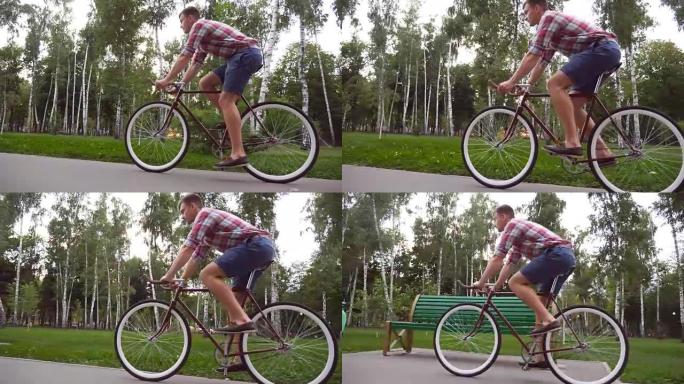 跟随年轻英俊的男人在户外骑老式自行车。运动男在公园骑自行车。健康积极的生活方式。侧视图特写