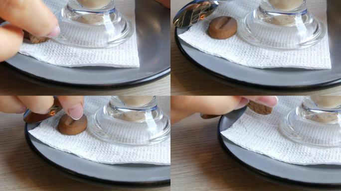女人在咖啡馆里转动一个碟子和一杯拿铁咖啡，碟子上放着一个咖啡豆形式的饼干