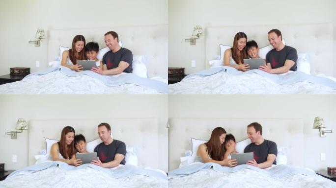 在床上使用数字平板电脑的家庭