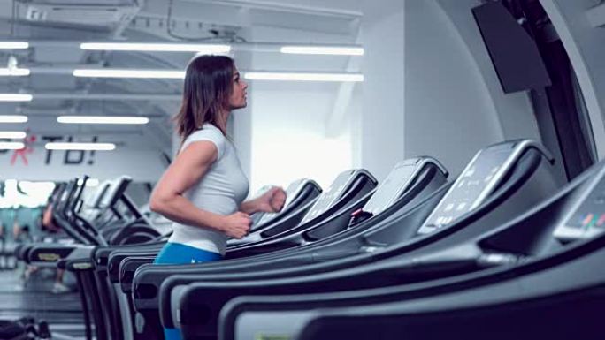 Adult woman runs on treadmill at the fitness centr