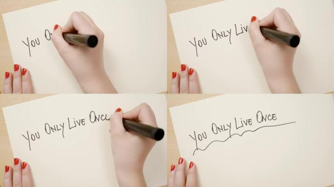 年轻女孩用手在白皮书上写你只活一次的信息，用黑色记号笔把它作为激励语