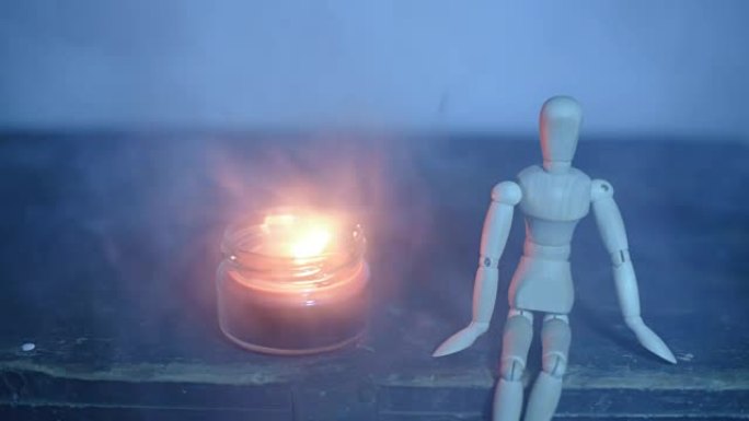 黑色背景上的木制娃娃，罐子里的蜡烛