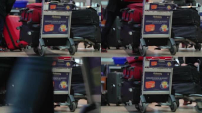 机场安检入口行李控制。扫描行李。带有大型红色行李箱的家庭通过入口控制装置，并将行李装载到手推车上