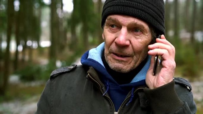 活跃的70岁老人在冬季森林中行走时通过手机聊天