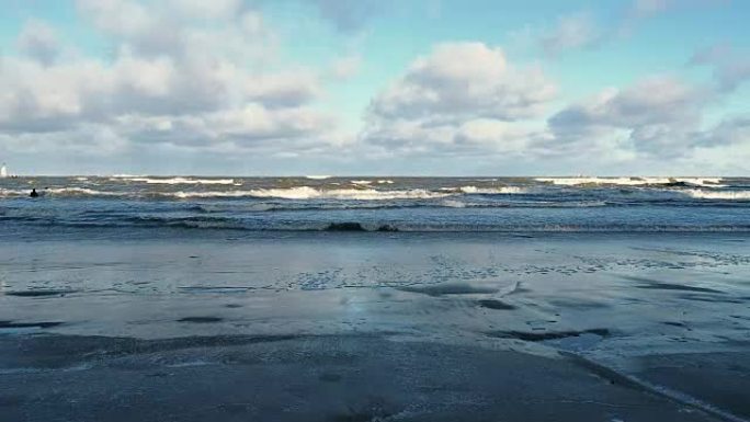 暴风雨过后的冬季沙滩。用泡沫卷大浪