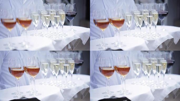 服务员用酒精饮料迎接客人。香槟、红酒、白葡萄酒放在托盘上。