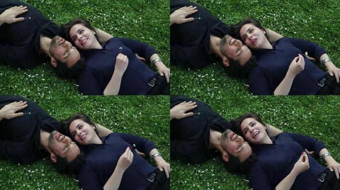 浪漫的情侣躺在草坪上轻柔地聊天