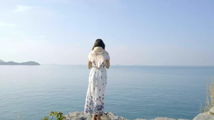 女人站在海上的石头上。