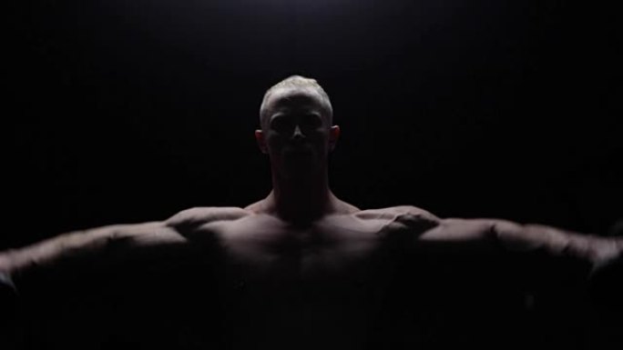 Shirtless bodybuilder workout in dark