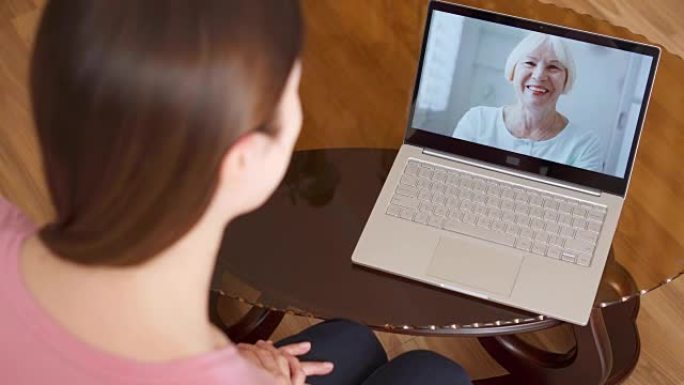 出国留学的女儿通过messenger应用程序与她的资深母亲在笔记本电脑上进行视频聊天