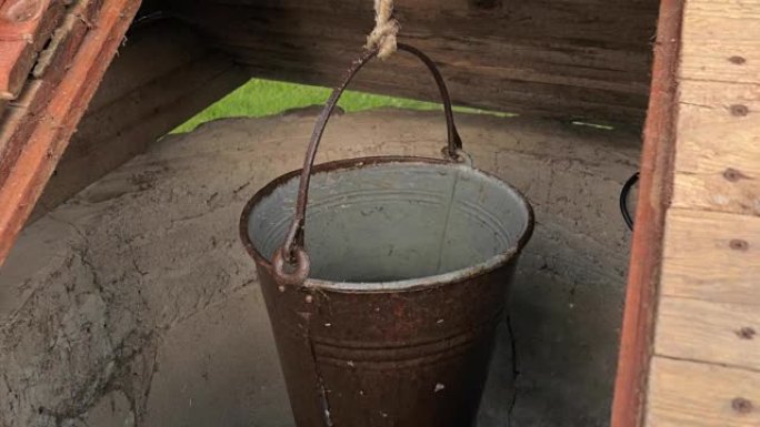 装满水的金属桶悬挂在农村井中