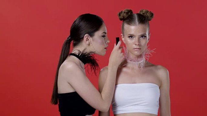 两个模特 (黑发和金发) 互相展示口红和尖叫。时尚视频。