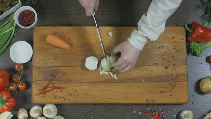 厨师切洋葱和胡萝卜。洋葱和胡萝卜作为做汤或另一道菜的配料。顶视图