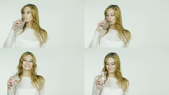 年轻女子在标题的框架空间中从白色背景上的玻璃杯中喝水