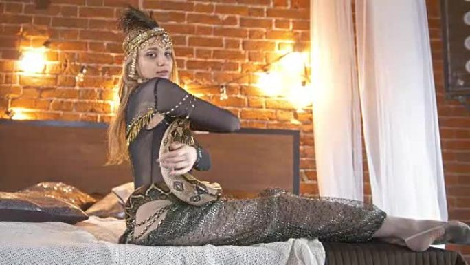 美丽的马戏团女演员在床上与蛇共舞