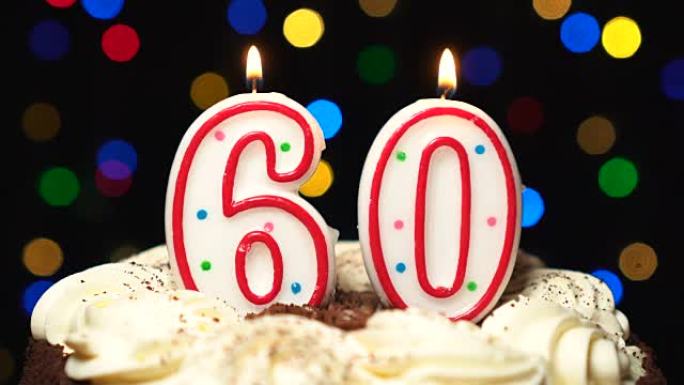 蛋糕顶部的60号-六十岁生日蜡烛燃烧-最后吹灭。彩色模糊背景