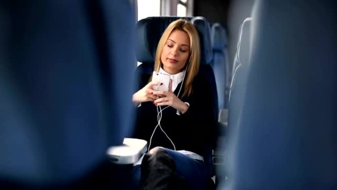 年轻女子在火车上旅行和听音乐