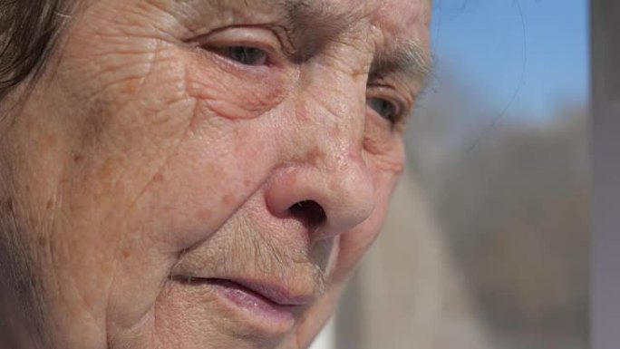 一位患有颤抖的眼睑的老妇人的悲伤面孔的特写