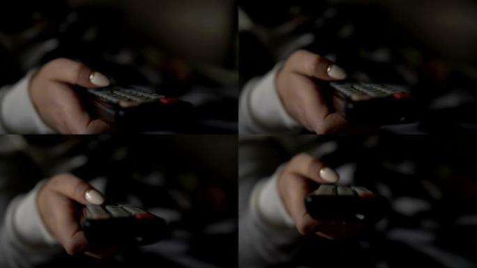 女人躺在沙发上，切换遥控器的频道，关闭电视遥控器的频道