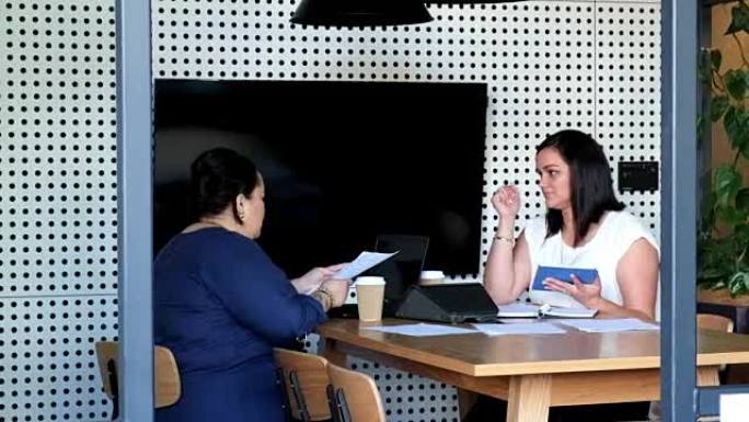 两名毛利女性员工在与平板电脑设备的商务会议上