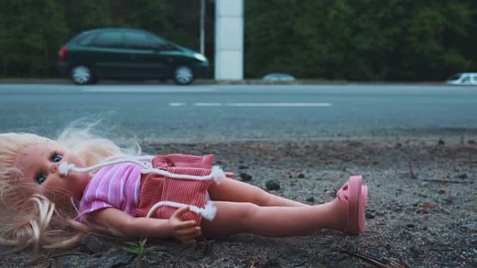洋娃娃掉在交通活跃的道路附近。许多汽车从后面驶来。慢动作。