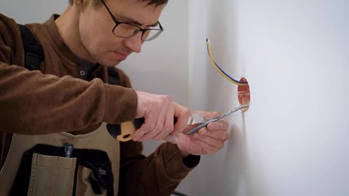 wireman正在使用房间内的文具刀剥离安装插座的电线，切割电缆护套