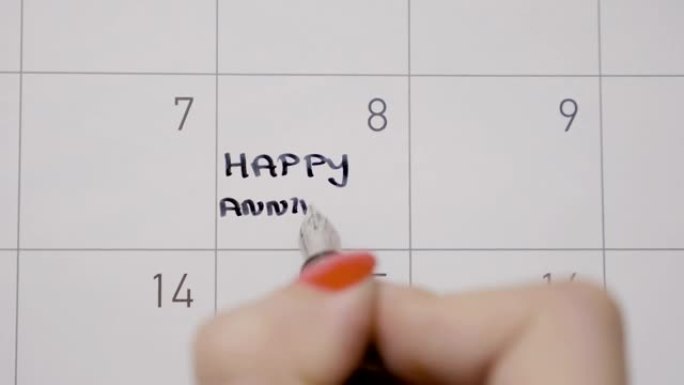 女人的手通过用黑笔写周年快乐来纪念日历上的日子