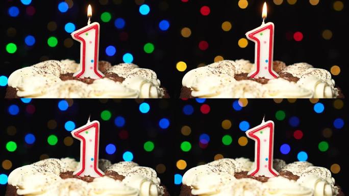 蛋糕上的第一号 -- 一根生日蜡烛燃烧 -- 最后吹灭。彩色模糊背景