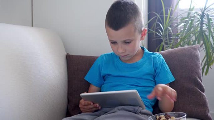 男孩独自坐在房间里时专注于屏幕平板电脑